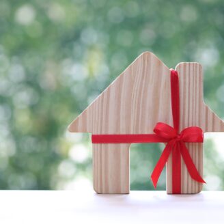 wooden cut out house with a red ribbon tied in a bow around it