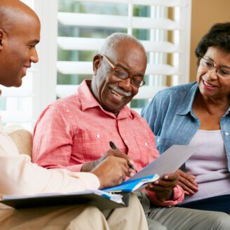 Mature African American Couple signs documents in hands of a younger man