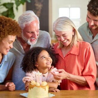 multigenerational family sitting in front of a cake