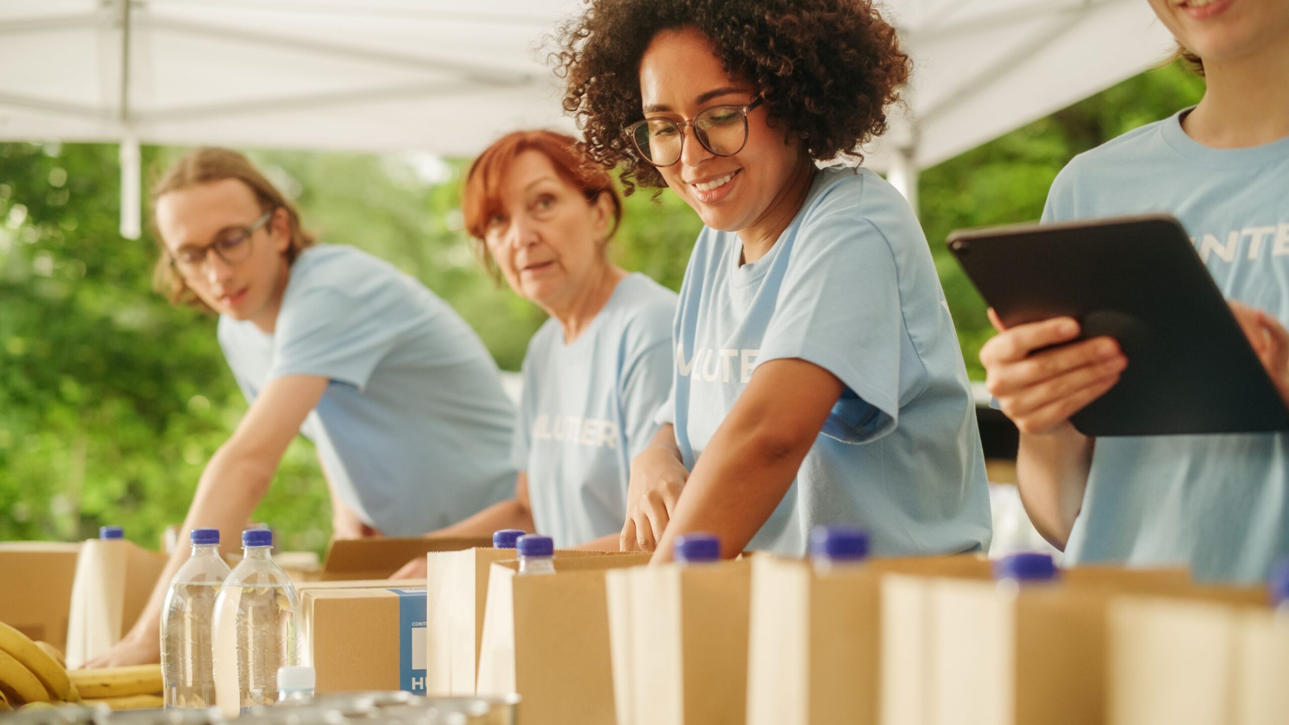 Volunteers fill grocery bags with food.