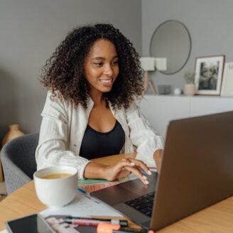 black woman sitting at a laptop typing and smiling